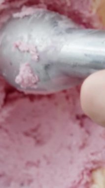 Dikey video. Dondurmanın üç farklı renginden pembe meyveli olanı seçiyorum ve özel bir kaşıkla topunu topluyorum..