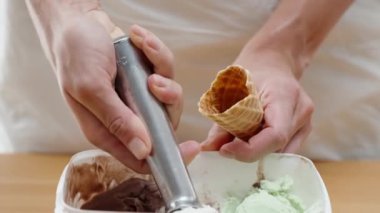 Kadının elleri özel bir kaşıkla waffle külahına dondurma topları atıyor..