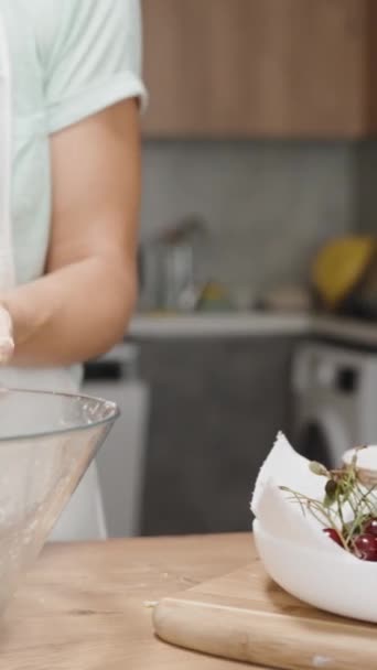 女性はプラスチック製のラップで生地を包み込み 洗濯機で手を洗うために台所の背景に移動します バーティカルビデオ — ストック動画