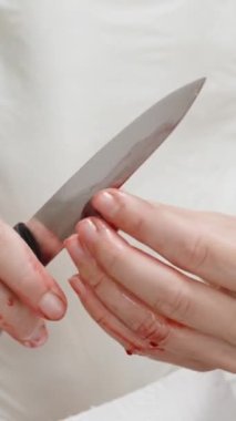 Kadın kirazı bıçakla ikiye bölüyor ve çukurları temizliyor. Dikey video.