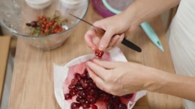 Kadın yavaş çekimde bıçakla kirazların koltuk altlarını dikkatlice kaldırıyor..