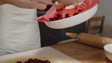 Kadın hamurun üzerine kalın bir katman taze doğranmış kiraz koyar..