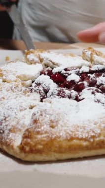 Kadın kiraz galetesinden bir parça kesiyor ve kameradaki dolguyu gösteriyor. Dikey video.