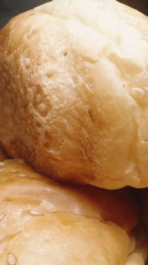 Sosisli sandviç ekmeği iki parçaya bölünüyor, siyah arka planda yakın plan. Dikey video.