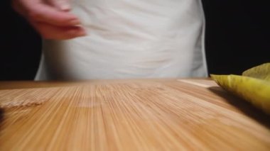 Kadın dilimlenmiş turşuları kesme tahtasının kenarına kaydırıyor kamera geriye doğru hareket ederken, süper yakın plan..