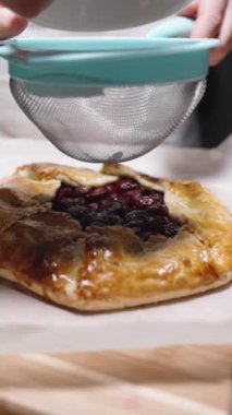 Bir eleğe toz şeker serperek, kiraz galonuna serpiyorlar. Ağır çekim. Dikey video.