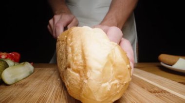 Masadaki sosislinin malzemeleri, ve kadın ekmeği ikiye bölüyor. Dolly kaydırıcı aşırı yakın çekim.