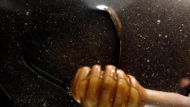 从下面的一层蜂蜜到玻璃杯 我把勺子浸在里面 在黑色的背景上画出一个心形 — 图库视频影像