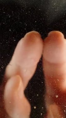 Dikey video. Aşağıdan, üzerine bal döküldüğü camın arkasından bak. Bir kadın, üzerinde parmakları olan bir kalp şekli çiziyor. Bal sevgisi kavramı..