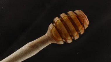 Özel ahşap bir bal kaşığı şeffaf camların üzerindeki ince bir bal katmanının üzerinde titreşen ışıkla duruyor. Yakın çekim..