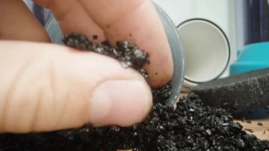 Adam kullanılmış bir kömür kömürü filtresini sökmüş ve parçacıklarını makro kameraya gösteriyor..