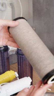 Dikey video. Adam su filtrelerini değiştiriyor ve eski, kirli filtreyi yakın planda gösteriyor..