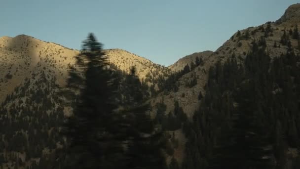 从被落日的最后一缕光芒照亮的高山山峰的移动的汽车上看到的风景 — 图库视频影像