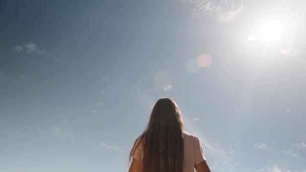 古代遺跡と岩の間を旅する若い女性は 太陽と背の高い山の背景に対して 彼女の手で彼女の髪を集めます — ストック動画