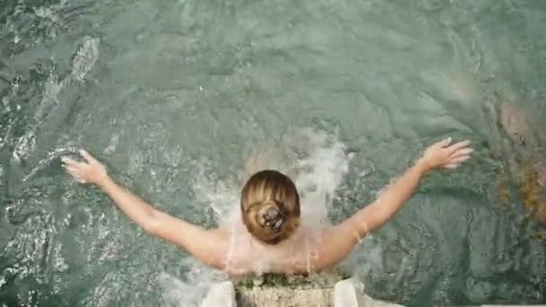在慢动作中 一个年轻的女人站在温泉的水流下 享受着这种感觉 双手在水里流过 顶部视图 — 图库视频影像