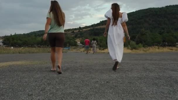 二人の女性とその先のカップルが夜の山に向かって岩の上を歩いています — ストック動画