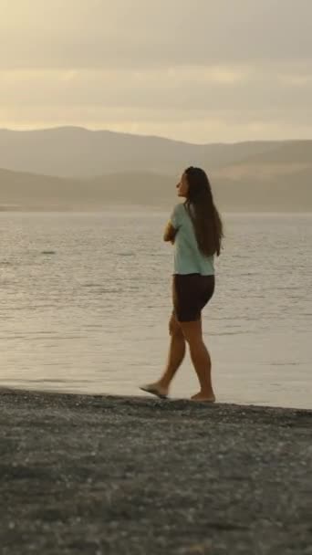 Μια Νεαρή Γυναίκα Περπατάει Στην Ακτή Μιας Λίμνης Στο Σάνσετ — Αρχείο Βίντεο