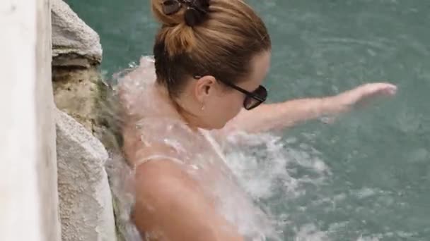 パムカレのクレオパトラのプールの水流の下に立っているメガネの若い女性のクローズアップ ホットスプリング ライフ — ストック動画
