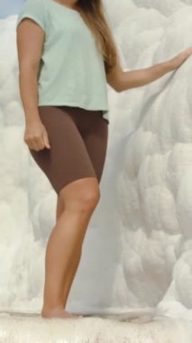 Dikey video. Maden suyu olan doğal havuzlar, Pamukkale geçitleri. Genç bir kadın kalsit yataklarını inceliyor ve dokunuyor..