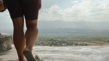 Pamukkale 'nin eşsiz doğal parkı beyaz kalsiyum travertinleriyle, yürümek için yüksek dağlarıyla, genç bir kadının gezindiği, ve ben onu takip ediyorum..