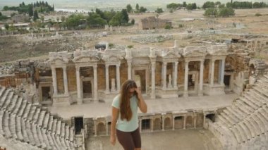 Genç bir kadın, antik amfitiyatronun, Hierapolis harabelerinin dik basamaklarına tırmanıyor..
