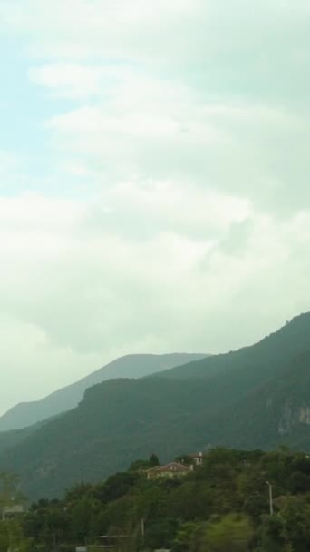 バーティカルビデオ 車の旅 それらの上に木や雲で覆われた山の窓からの眺め — ストック動画