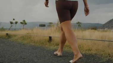 Genç bir kadının Dağ Gölü 'ne doğru Rocky Yolu boyunca yürümesini arkadan izleyin. Hava bulutlu..