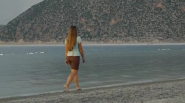 Batan güneşten gelen altın ışık, dağ gölünde yürüyen genç bir kadını aydınlatır..