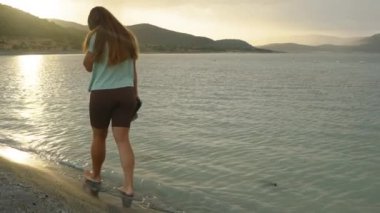 Dağların arkasındaki Güneş ışınları bulutların arasından parlayarak Dağ Gölü 'nün suyunu aydınlatıyor. Genç bir kadın suyun üzerinde güneşe doğru yürüyor..