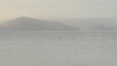 Dağların ortasındaki Büyük Gölün Panoraması. Bulutlu hava ve batan güneşin ışınları bulutları delip geçiyor..