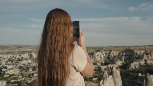 一位年轻女子正在土耳其的戈里梅自然公园的手机上旅行 拍摄美丽的空中风景 全景尽收眼底 — 图库视频影像