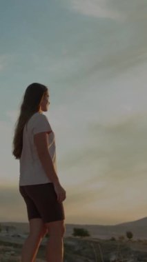 Dikey video. Akşamları, genç bir kadın dağlarda yürüyüşe çıkar. gün batımı