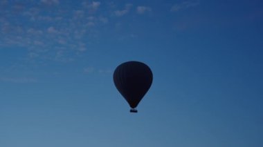 İçinde insanlar olan devasa bir sıcak hava balonu havada, hava hala karanlık ve şafak yaklaşıyor..