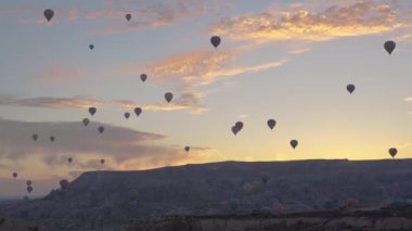 Yüzlerce sıcak hava balonunun insanları havada taşıdığı kanyonda güzel bir gün doğumu. Güneşli altın bulutların ve yükselen uçurumların ardında..