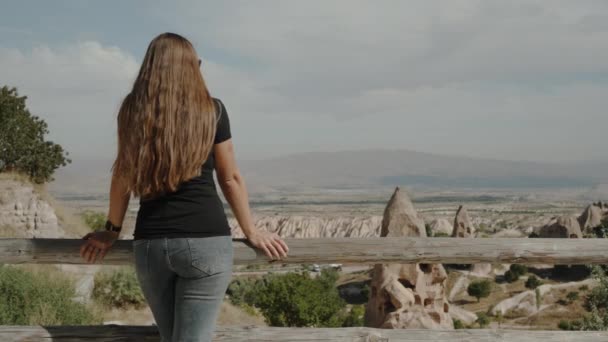 山の高い若い女性は 崖に彫られた古代トルコの町や家を賞賛し — ストック動画