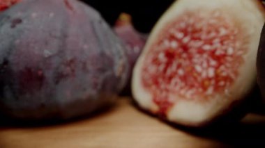 Dilimlenmiş incir meyveleri masaya saçılmış, kamera iki yarıdan geçiyor. Dolly kaydırıcı aşırı yakın çekim.