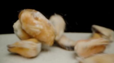 Donmuş ve temizlenmiş midyeler yavaş çekimde tabağa düşer. Dolly kaydırıcı aşırı yakın çekim.