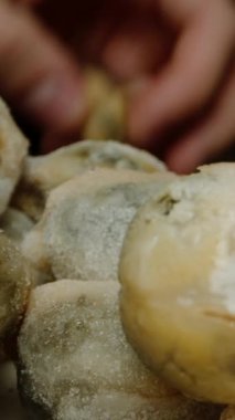 Dikey video. Büyük bir miktar donmuş midye, üst üste istifliyor.