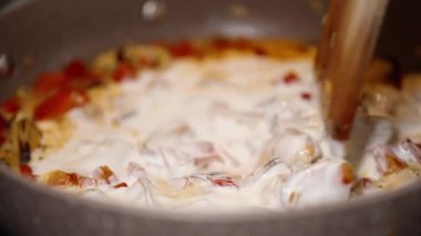 Midyeleri kremalı sosla karıştırıyorum sebzelerle Tahta kaşık kullanarak, Yakın plan.