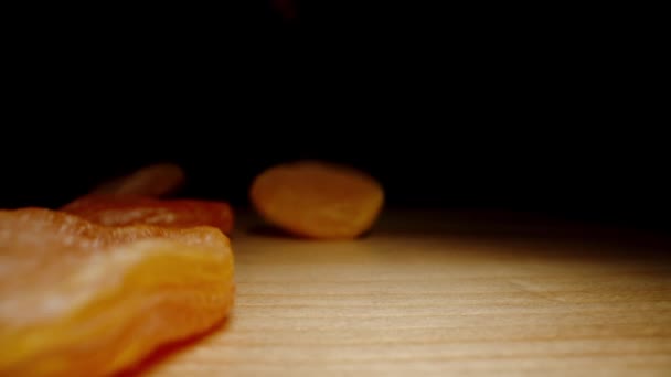 Sušené Meruňky Dopadají Dřevěný Stůl Černém Pozadí Pomalým Pohybem Dolly — Stock video