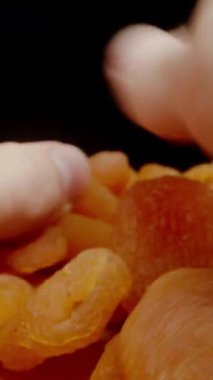 Dikey video. POV, İki Elli Bir Avuç Kurutulmuş Kayısı Birlikte. Dolly kaydırıcı aşırı yakın çekim.