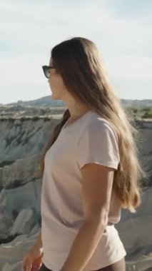 Dikey video. Genç kadın zirveye sakin bir şekilde yürüyor ve Türkiye 'deki Aşk Vadisi' ne yüksek bir açıdan bakıyor..