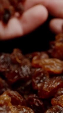 Dikey video. POV, iki el birlikte bir avuç kuru üzüm toplar. Dolly kaydırıcı aşırı yakın çekim.