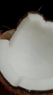 Dikey video. Masada iki parçaya ayrılmış kıllı bir hindistan cevizi. Siyah arka plan. Dolly kaydırıcı aşırı yakın çekim.