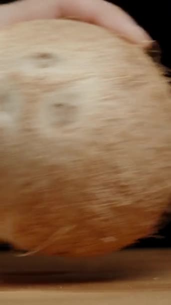 バーティカルビデオ 男の手はココナッツを揺さぶり 内部のジュースの存在をチェックする スローモーション ブラックバックグラウンドでクローズアップ — ストック動画