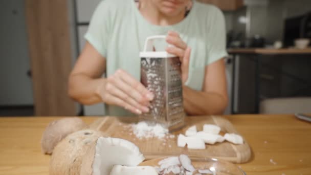 Молодая Женщина Кухне Разрезает Кокосовый Орех Куски Помощью Металлической Терки — стоковое видео