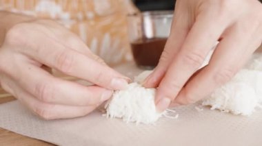 Kadın, Hindistan cevizi rendelenmiş etinden hindistan cevizi şekeri yapıyor. Yakın plan.