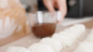 Kadın hindistancevizi şekeri hazırlıyor, Bir tanesini erimiş çikolataya batırıyor. Yavaş Çekimde, Yakın Çekimde.