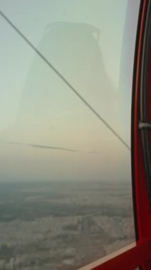 Dikey video. Gezgin genç bir kadın dağlarda bir teleferik kulübesinde oturuyor, gün batımını seyrediyor ve olumlu bir şeyler düşünüyor..