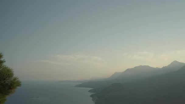 海岸沿いの山々にあるパノラマハイ 太陽は山の後ろにほぼセットされ その最後のレイは山腹に沿って丘を横切って広がっています — ストック動画
